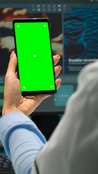 Pohled zezadu na mikrobiologa při pohledu na mobilní telefon se zeleným mokupem — Stock fotografie