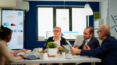 Odaklanmış kadın yönetici ve çok ırklı ekip evrak işlerini inceliyor