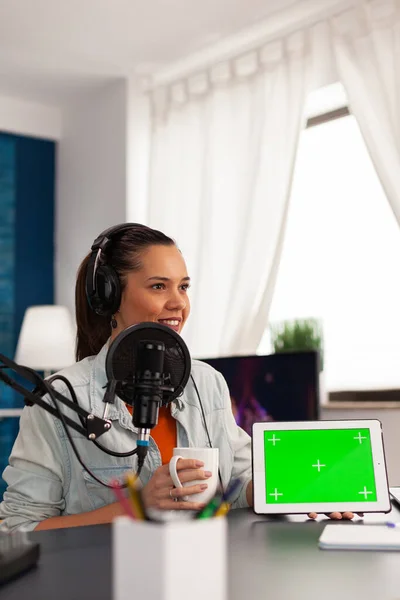 Famous blogger influencer filming video of tablet with green screen in home studio podcast
