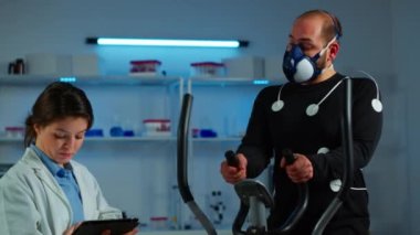 Doktor bilim sportmen dayanıklılığını ölçerken tablet üzerinde yazıyor.