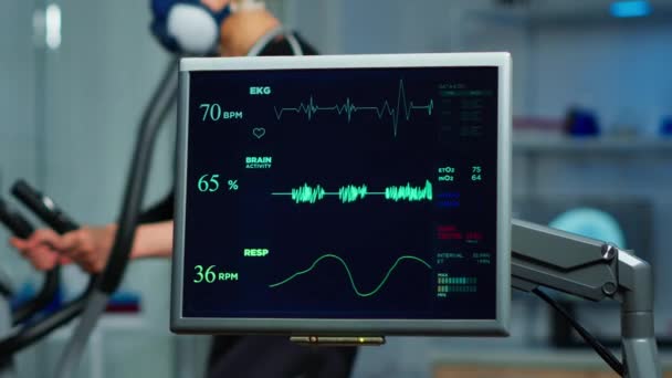 Monitor que muestra el escaneo EKG de atleta corriendo en cross trainer — Vídeo de stock