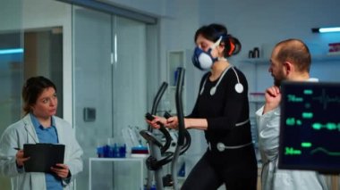 Maskeli hasta çapraz çalıştırıcıda koşarken doktor panoda witing yapıyor