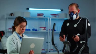 Çapraz antrenörde çalışan vücuda maske ve elektrotlar takılı bir sporcu
