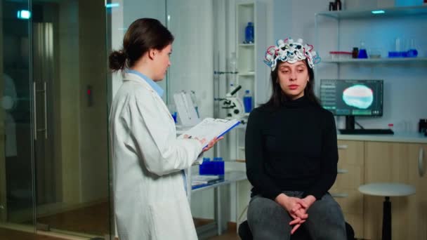 Neuroloog arts vraagt symptomen van de patiënt het nemen van notities op het klembord — Stockvideo
