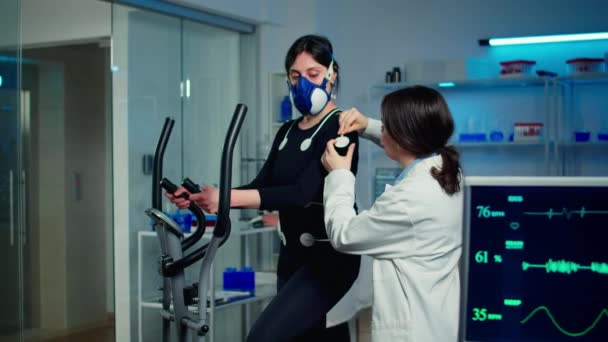 Mujer atleta con máscara corriendo en cross trainer — Vídeos de Stock