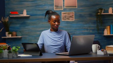Laptop ve tableti aynı anda kullanan Afrikalı bir kadın.