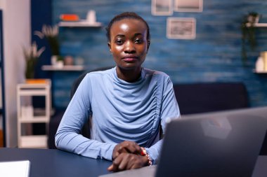 Masasında dizüstü bilgisayarla oturan koyu tenli serbest çalışan.