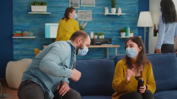 Vrienden met beschermmasker socialiseren tijdens het feest zitten op de bank — Stockvideo