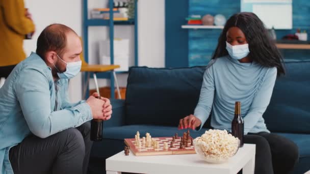 Man håller flaska öl medan man spelar schack med afrikansk kvinna — Stockvideo