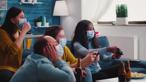 Vänner med masker som håller styrenheter spelar TV-spel — Stockvideo