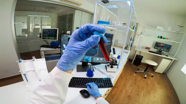 POV of scientist analysing blood sample from test tube