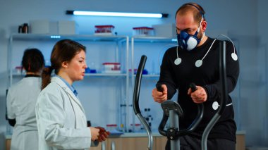 Çapraz antrenörde çalışan vücuda maske ve elektrotlar takılı bir sporcu