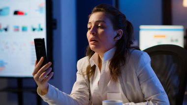 Girişimci, kablosuz kulaklıklı akıllı telefon kullanarak sanal toplantı yapıyor.