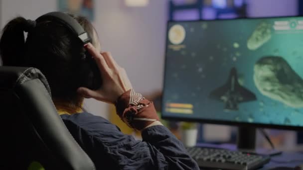 Gericht vrouw gamer zitten op bureau zetten op headset — Stockvideo