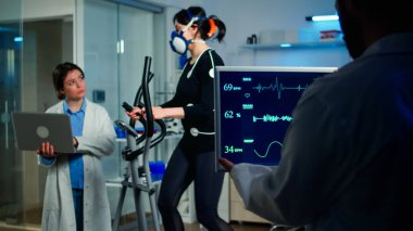 Dizüstü bilgisayarı tutan ve EKG verilerini kontrol eden bir doktor.