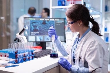 Bilim adamı biyoloji hastanesi testi için numuneyi mikro pipetin içine inceliyor.