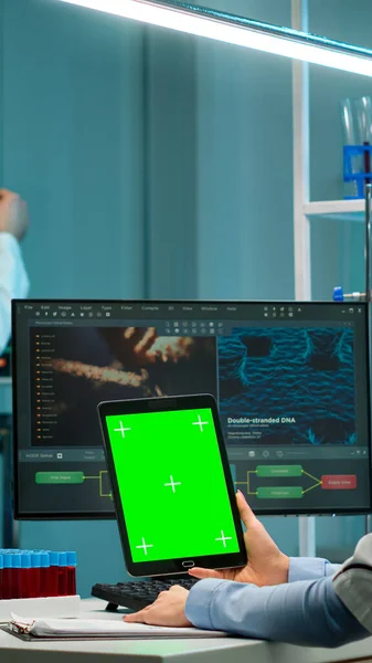 Microbiologist working on notepad with green chroma key display