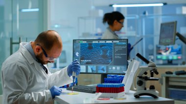 Modern laboratuardaki test tüplerini doldurmak için mikro pipet kullanan bilim adamı.