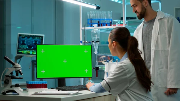 Female scientist reading on computer with mock-up green screen