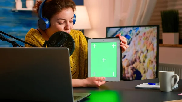 Influencer holding tablet with green screen speaking during podcast