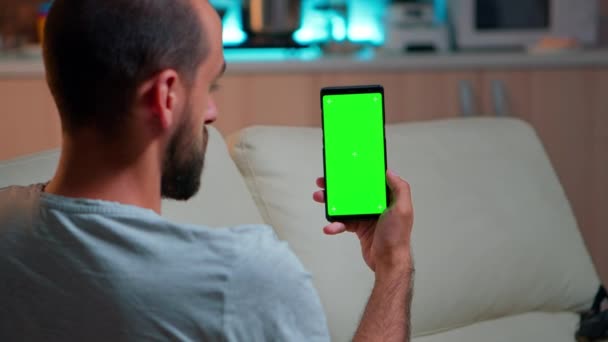 Расслабленный человек смотрит на смартфон с макетом зеленого экрана хрома дисплей ключа — стоковое видео
