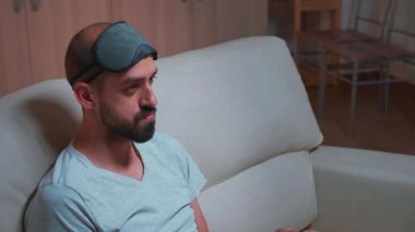 Uyku maskeli profesyonel oyuncu televizyon karşısında oturmuş video oyunları oynuyor.
