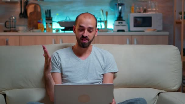 Hvid mand sidder på sofaen i pyjamas arbejder på bærbar computer – Stock-video