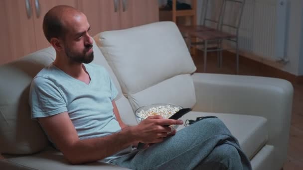 Maschio caucasico che si rilassa sul divano con ciotola di popcorn in mano mentre guarda serie di film — Video Stock
