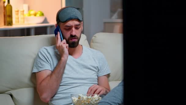 Hombre cansado con máscara de dormir poner hablando en el teléfono inteligente — Vídeos de Stock