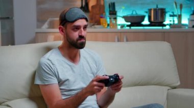 Kanepede oturup futbol oynayan sinirli profesyonel oyuncu.