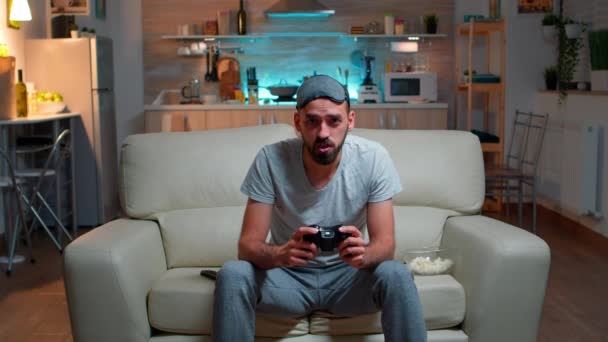 Hombre enfocado sosteniendo joystick mientras está sentado frente a la televisión — Vídeo de stock