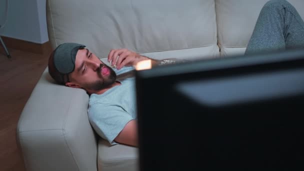 Homme caucasien avec masque de sommeil oculaire manger du pop-corn tout en regardant spectacle de télévision de divertissement — Video