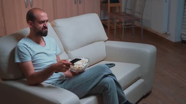 리모 콘을 사용하여 텔레비전 앞에 앉아 있는 집약적 인 사람 — 비디오