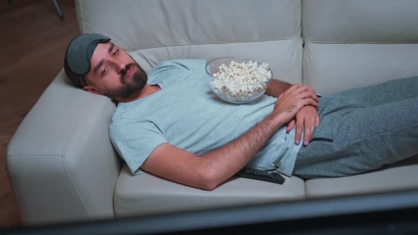 Hombre cansado tumbado en el sofá viendo el espectáculo de películas — Vídeos de Stock