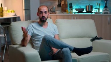 Serbest çalışan bir adam kanepeye oturmuş iş görüşmelerini kaydediyor.