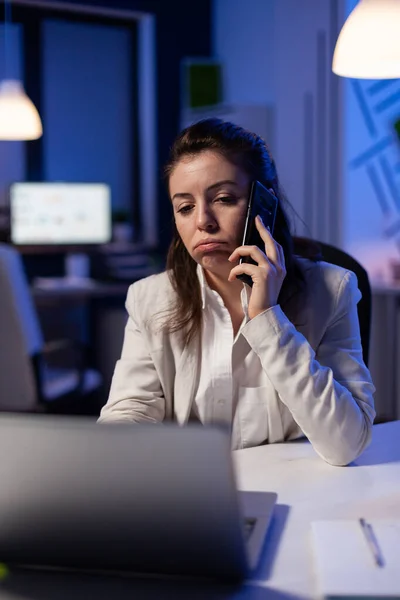 Freelancer corporativo cansado conversando por teléfono mientras trabaja agotado para las estadísticas económicas — Foto de Stock