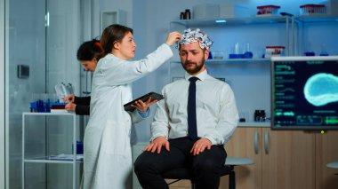 Beyin dalgası tarayıcı kulaklıklı bir adam profesyonel doktoru ziyaret ediyor.