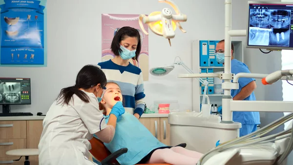 Dentist technician with gloves explaining the process to kid patient