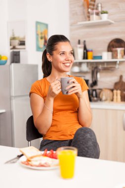 Bir yudum kahveden sonra gülümsüyor.