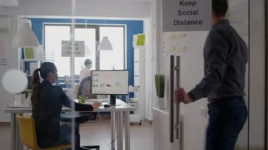 Yüzü maskeli bir iş adamı meslektaşıyla dirseğine dokunuyor.