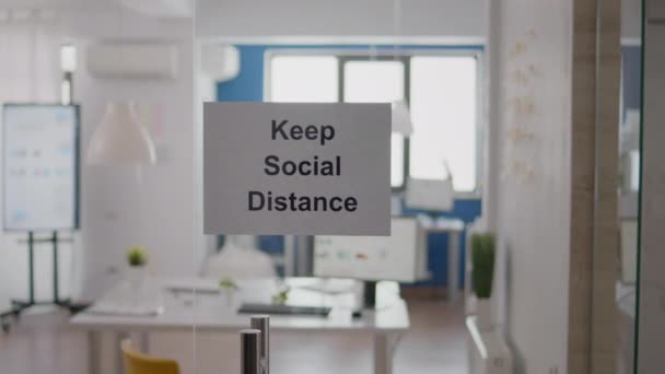 Keep Social Distance sign on glass wall in empty office — Stock Video