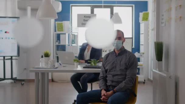 사무실 책상에 앉아 의료용 마스크를 쓴 사업가의 모습 — 비디오