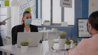 Tıbbi maskeli iş adamları şirket ofisinde birlikte çalışıyorlar.