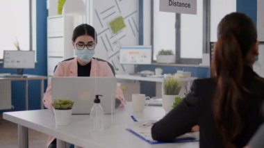 Tıbbi maskeli iş adamları yeni normal ofiste birlikte çalışıyorlar.