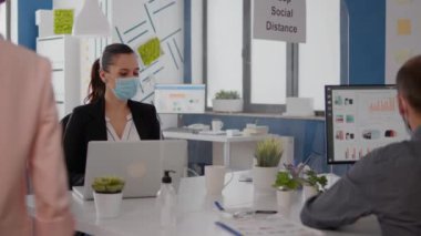 Yüz maskesi takan iş arkadaşları yeni normal ofiste birlikte çalışıyorlar.