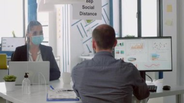 Şirket ofisinde çalışan yüz maskeli iş adamları güvenlik önlemlerini korumak için gerekli önlemleri alıyor.