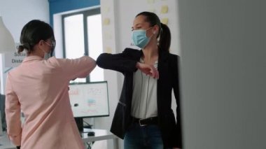 Koronavirüs enfeksiyonunu önlemek için yüz maskeli bir iş kadını dirseğine dokunuyor.