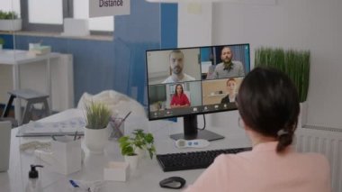 Executive freelancer looking into monitor talking with coworkers on online videocall