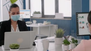 İş yerindeki bilgisayarlarda çalışan koruyucu yüz maskesi takan serbest çalışanlar