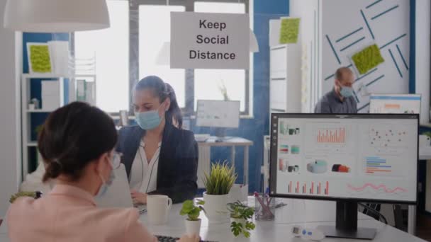 Ділові люди з медичними масками для обличчя сидять в новому звичайному офісі компанії — стокове відео